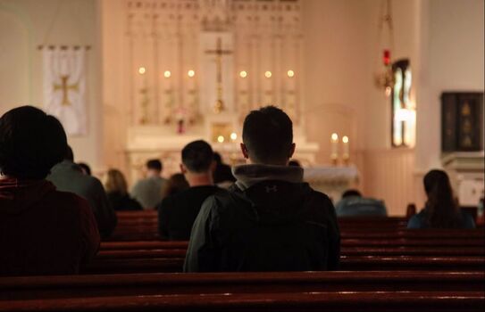A picture of 12 WWU students spread out praying in church pews with their backs facing.